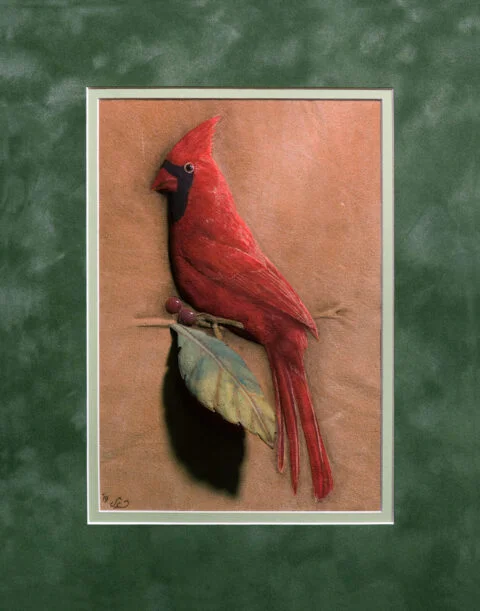 Photo of the Cardinal burned on buckskin leather and finished with natural pigments and primitive tools.