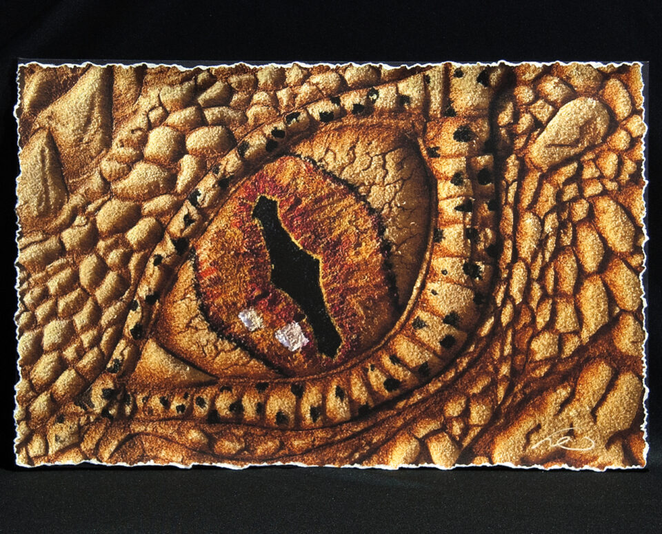 Photo of Cave Geek Art's Smaug's Eye burned on buckskin leather and finished with natural pigments and primitive tools showing the hand-deckled edges.